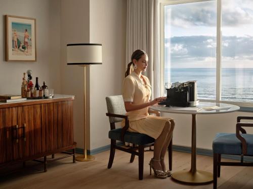 a woman sitting at a table in a hotel room at The Georgian Hotel in Los Angeles
