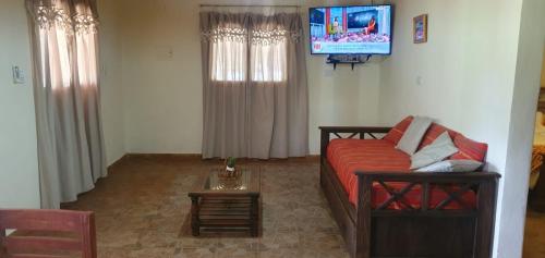 uma sala de estar com um sofá e uma televisão em La Soñada de La Majadita em San Agustín de Valle Fértil