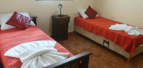 um quarto com duas camas com lençóis vermelhos e brancos em La Soñada de La Majadita em San Agustín de Valle Fértil