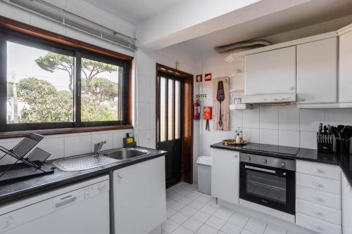 kuchnia z białymi szafkami, umywalką i oknem w obiekcie Home Out Vila do Lince - 8 Bedrooms, Heated Pool & Gym - Marina Vilamoura w mieście Vilamoura