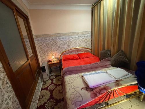 a small bedroom with two beds with red pillows at Dar Echorafa in Marrakesh