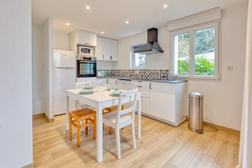 a white kitchen with a white table and chairs at La Dune de Sable Sainte Marguerite in Pornichet