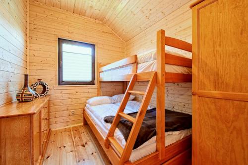 a bedroom with bunk beds in a wooden cabin at DOMKI JANTAR PREMIUM in Bobolin