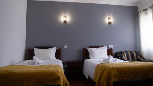 um quarto com duas camas com lençóis amarelos e luzes em Casa das Termas nas Termas de São Pedro do Sul