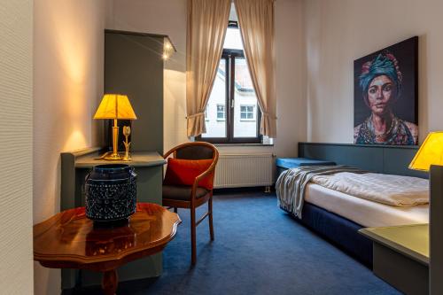 - une chambre avec un lit, un bureau et une table dans l'établissement Hotel Mauritius, à Crimmitschau