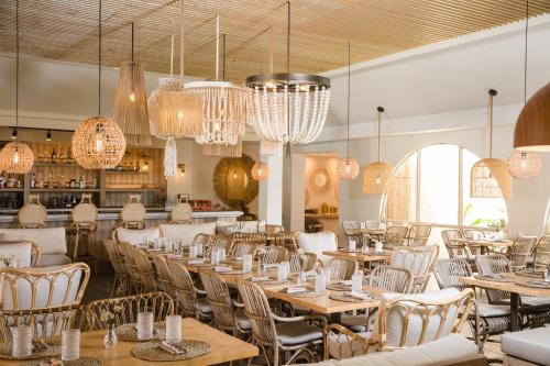 a dining room with tables and chairs and chandeliers at Wyndham Palmas Beach and Golf Boutique Resort in Humacao