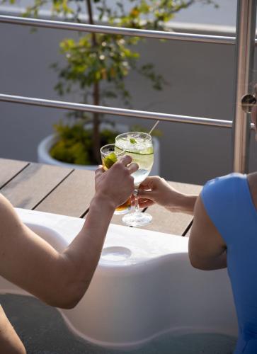 two people sitting in a bath tub with a drink at TH HOTEL & VIVIENDA in Tepatitlán de Morelos