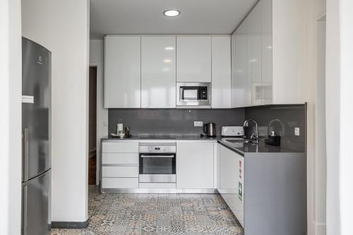 a white kitchen with white cabinets and appliances at Home Out Rooms & Apartments in Lisbon