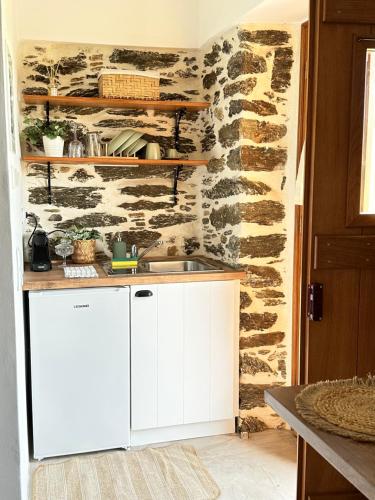 a kitchen with white cabinets and a stone wall at Peristerionas Estate in Karistos