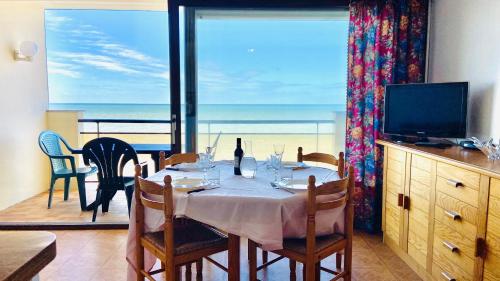 a dining room with a table and a view of the ocean at Studio lumineux face mer à Cayeux sur mer in Cayeux-sur-Mer