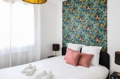 - une chambre avec un lit blanc et un papier peint floral dans l'établissement Hysope, à Annecy