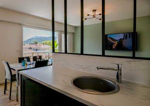 une cuisine avec un évier, une table et une fenêtre dans l'établissement Hysope, à Annecy