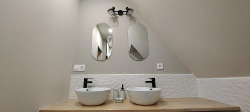 a bathroom with two white sinks and two mirrors at Les Délices de la Vie in Le Mesnil-Germain