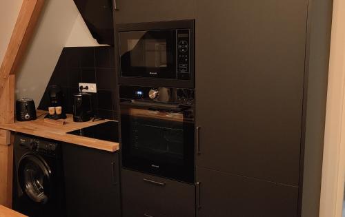 eine Küche mit einer Mikrowelle, einer Waschmaschine und einem Trockner in der Unterkunft Les Délices de la Vie 