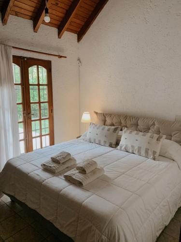 una camera da letto con un grande letto bianco con asciugamani di Casa Amelia a Ciudad Lujan de Cuyo