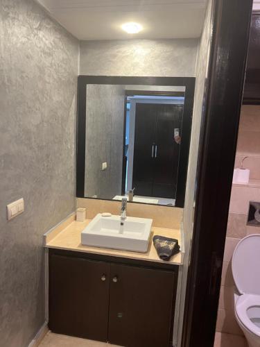 a bathroom with a sink and a mirror and a toilet at Corniche apartments in Casablanca