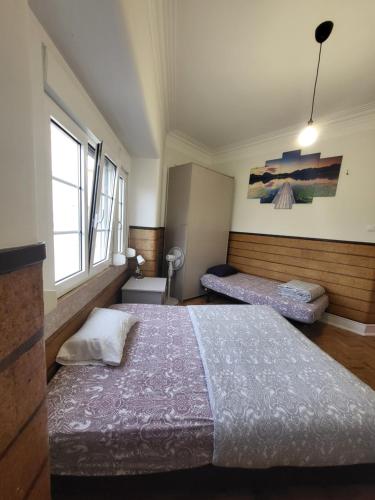 ein Schlafzimmer mit zwei Betten und zwei Fenstern in der Unterkunft Rainbow Guest House in Lissabon
