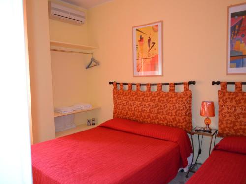 una camera con due letti con lenzuola rosse di A Casa di Carla a Terni