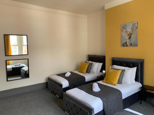 two beds in a room with yellow walls at Balfour - Beautiful refurbished spacious 3 bedroom Gateshead flat in Gateshead