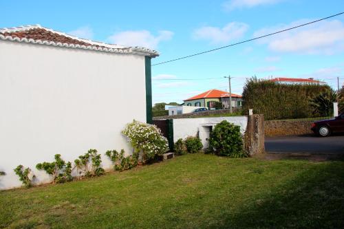 a white house with a yard next to a building at Casa do Sr. Alberto in Praia da Vitória