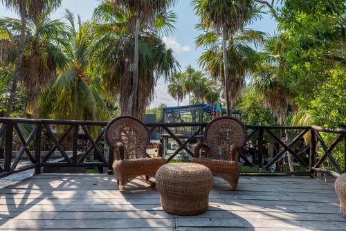 a patio with wicker chairs and tables and palm trees at Alquimia Hotel Boutique in Tulum