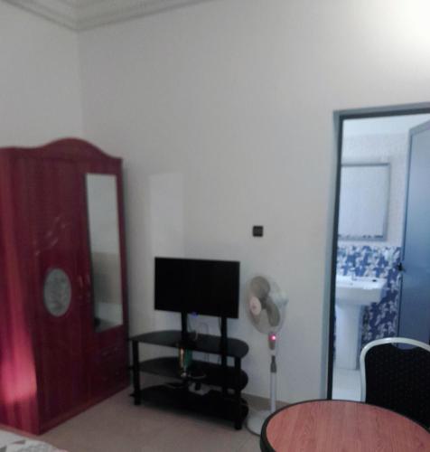 een woonkamer met een televisie en een spiegel bij Appartement meublé à Saint-Louis in Saint-Louis