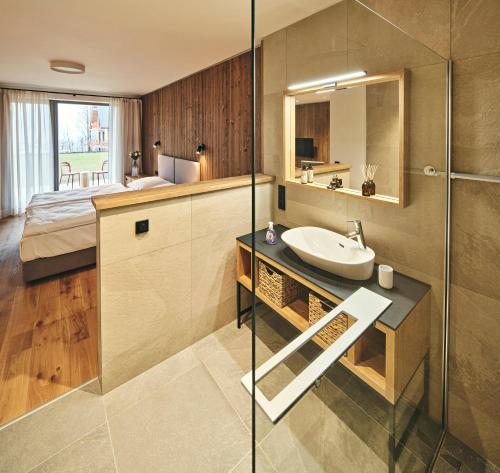 a bathroom with a sink and a shower and a bed at Aldrov Resort in Vítkovice