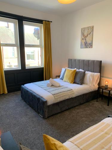a large bed in a room with two windows at Faraday - Central location Ideal for contractors and visiting Newcastle Free Wifi Free Parking in Gateshead