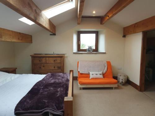 um quarto com uma cama e uma cadeira laranja em The Coach House 