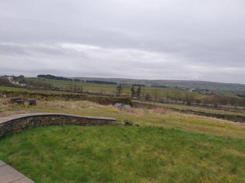 a view of a field of grass with a bench at The Coach House in Baxenden