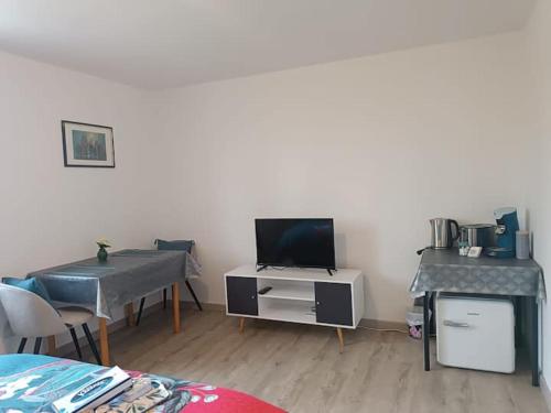 a living room with a table and a desk with a television at Chambre privée in Montaigu-Vendée