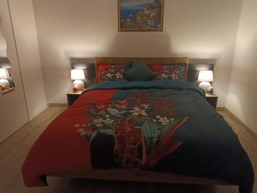 sypialnia z łóżkiem z czerwonym kocem i 2 lampami w obiekcie Chambre privée w mieście Montaigu-Vendée
