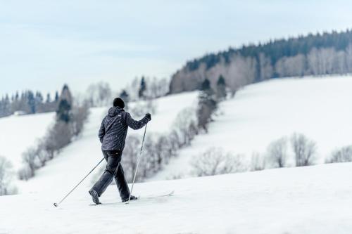 a man is cross country skiing down a snow covered slope at Aldrov Resort in Vítkovice