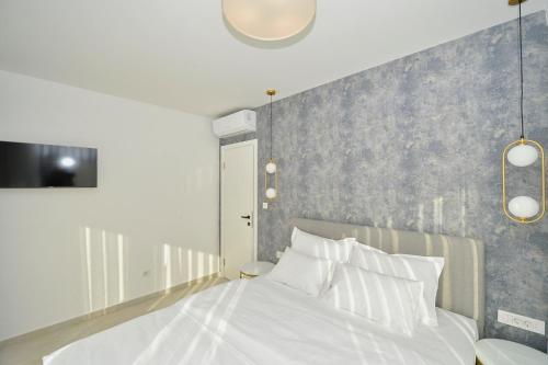 a bedroom with a white bed with a gray wall at Solaris Lux Apartments in Kotor