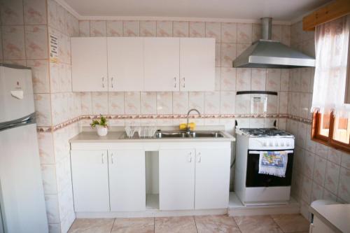 La cuisine est équipée de placards blancs, d'un évier et d'une cuisinière. dans l'établissement Hostal Chaxa, à San Pedro de Atacama