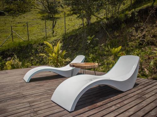 two white chairs and a table on a wooden deck at All Natural Glamping in Copacabana