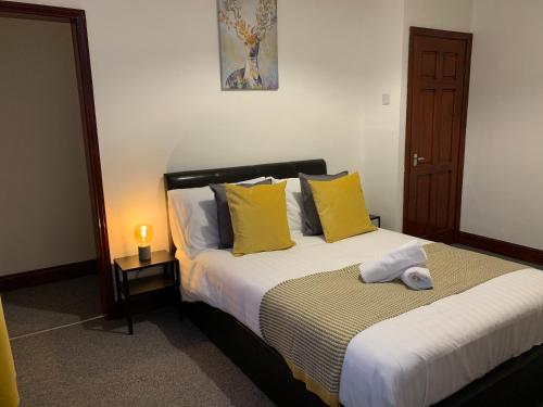 a bedroom with a large bed with yellow pillows at Rodsley - 2 bedroom 1st floor flat Free Parking WiFi and Netflix in Gateshead