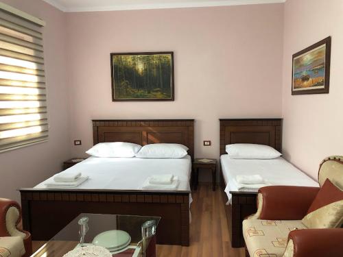 a bedroom with two beds and a table and a couch at Villa Garden in Berat