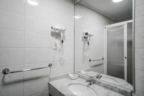 a bathroom with a sink and a shower and a phone at Hotel Melillanca in Valdivia