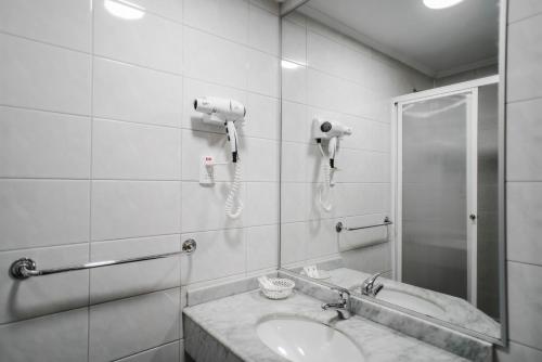 baño con lavabo, ducha y teléfono en Hotel Melillanca, en Valdivia