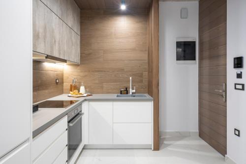 a kitchen with white cabinets and wooden walls at Disegno Residences in Chania Town