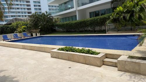 una piscina frente a un edificio con sillas en Apartamento Cartagena, en Cartagena de Indias