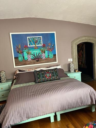 墨西哥城的住宿－Gallery and Boutique BNB in San Angel Inn，卧室配有一张床,墙上挂有绘画作品