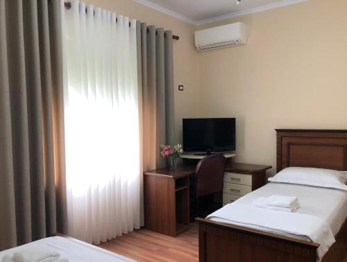 a bedroom with two beds and a desk with a television at Villa Garden in Berat