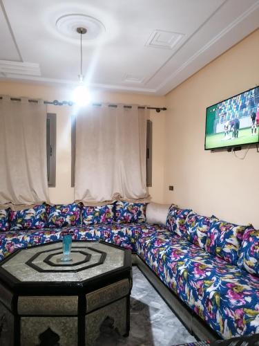 uma sala de estar com um sofá e uma televisão em Le bel abri em Meknès