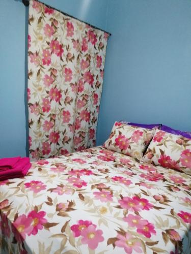 a bed with a floral comforter and two pillows at Le bel abri in Meknès