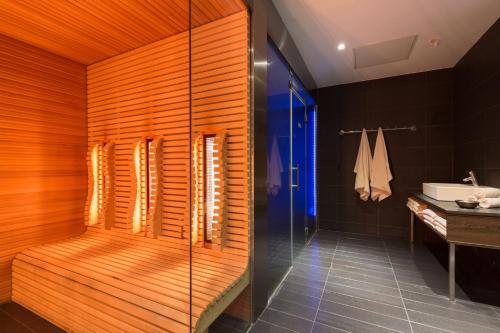 ein Bad mit einer Dusche und einer Holzwand in der Unterkunft Leonardo Royal Hotel Den Haag Promenade in Den Haag