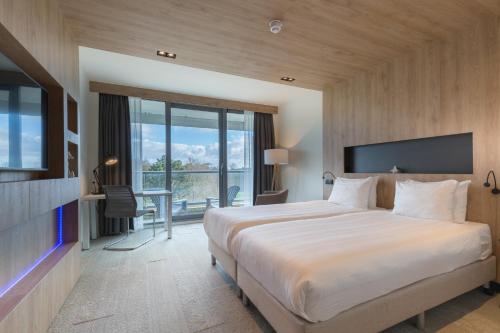 Cette chambre comprend un grand lit et un bureau. dans l'établissement Leonardo Royal Hotel Den Haag Promenade, à La Haye
