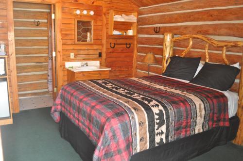 - une chambre avec un lit dans une cabane en rondins dans l'établissement Crooked Creek Guest Ranch, à Dubois