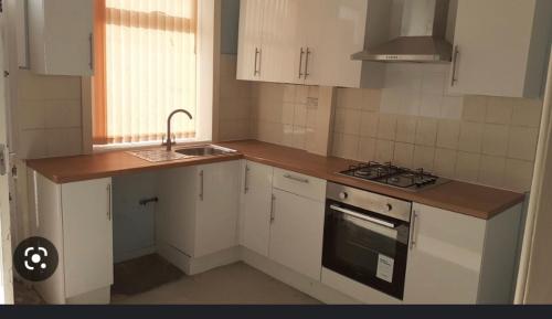 a kitchen with white cabinets and a sink and a stove at New room in Bradford